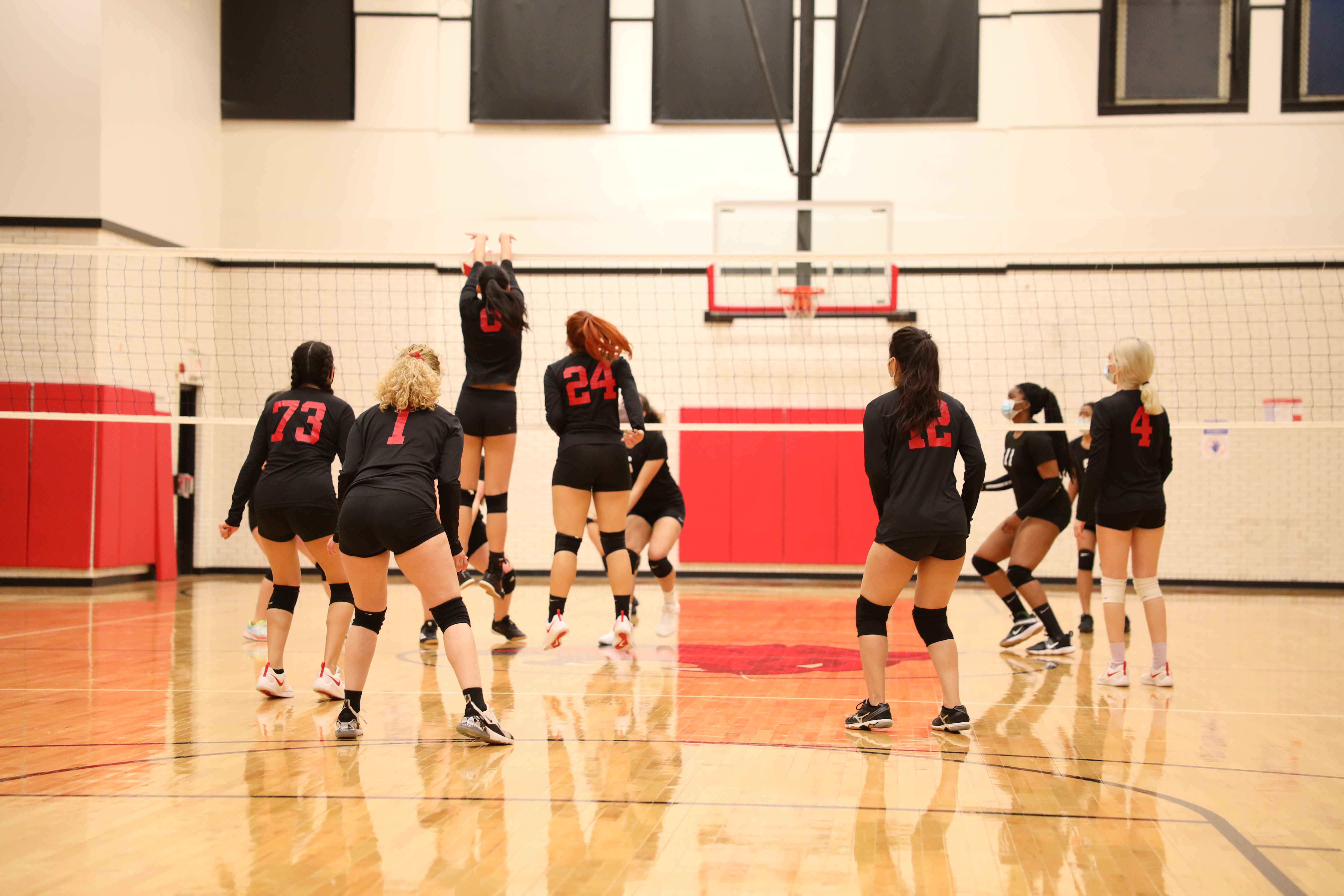 Wearing a black and red jersey with a #9. Blocking the ball